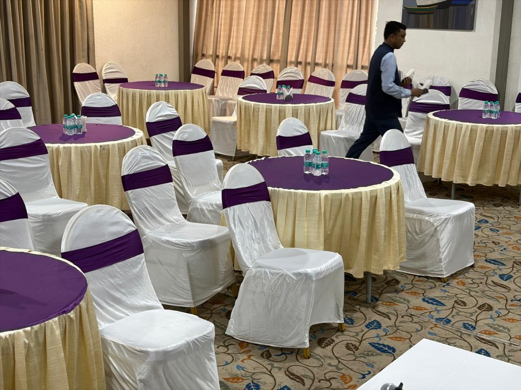 Banquet hall at Hotel Chaitali with purple table overlays and a stage