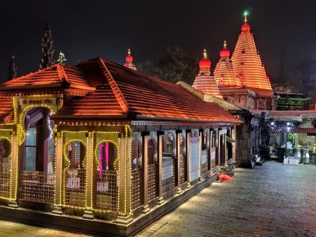Mahalaxmi Temple, Kolhapur, lit at night with shikharas and a red-tiled courtyard building